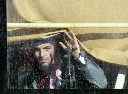 Un rebelde sirio mira a través de las ventanas del autobús que le llevará fuera del barrio de El Waer en la ciudad siria de Homs.