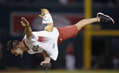 El artista Christian Stoinev, con su perro Scooby, actúa antes del partido de béisbol entre los Diamondbacks de Arizona y los Rockies de Colorado.