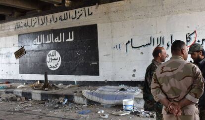 Militares sirios al lado de un grafiti pintado por el Estado Isl&aacute;mico en Alepo, la semana pasada.