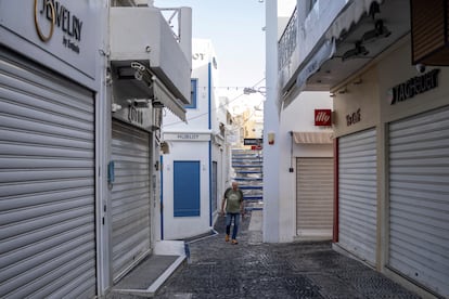 Un hombre camina este martes entre tiendas turísticas cerradas, la mayoría fuera de temporada, tras un aumento de la actividad sísmica en la isla de Santorini.