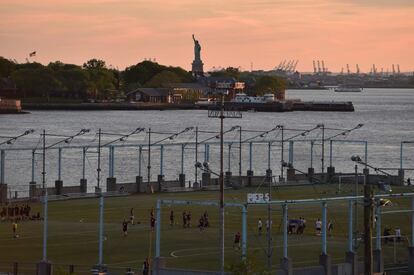 Cancha de fútbol en el Brooklyn Bridge Park de Nueva York frente a la Estatua de la Libertad al atardecer.