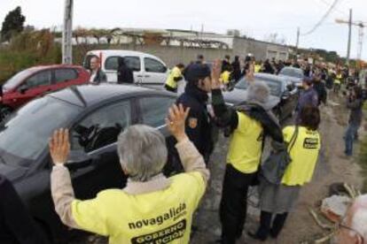 Efectivos de la polica junto a los afectados por las participaciones preferentes que se han concentrado hoy ante la explanada de la nueva depuradora de Vigo, donde han retenido en el interior de las instalaciones durante unos 45 minutos a las autoridades que realizaban una visita a las obras de esta infraestructura.Entre las autoridades figuraban el delegado del Gobierno en Galicia, Samuel Jurez, el conselleiro de Medio Ambiente, Agustn Hernndez, el subdelegado del Gobierno, Antonio Coello, y la directora general de Aquanorte, Isabel Prez-Espinosa, entre otras.