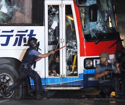 Un policía intenta abrir a golpes la puerta del autobús secuestrado. Al otro lado, un cuerpo que parece ser el del secuestrador.