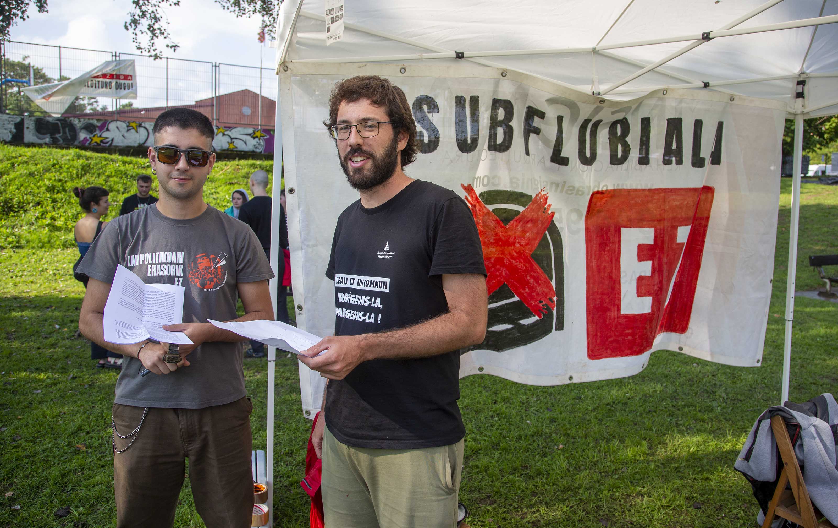 Dos jóvenes ecologistas reparten información sobre el prouyecto subfluvial de la ría de Bilbao en una acampada de protesta celebrada en Leioa (Bizkaia).