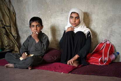 Ramin, de 7 años (izquierda), junto a su hermana Shola, de 9, que vende bolsas de plástico en un mercado antes de acudir al colegio.