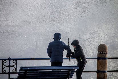 Turistas se acercan a ver el mar en la playa del Camello en Santander, durante el paso del temporal de invierno Bruno por Santander, que ha dejado rachas muy fuertes de viento en Cantabria, el 27 de diciembre.