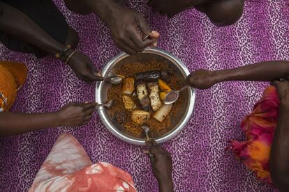 Un grupo de personas come 'ceebu jën' en la calle; es un plato tradicional de la cocina senegalesa compuesto de arroz, pescado y legumbres, que ha sido recientemente incluido en la lista de Patrimonio de la Humanidad por la UNESCO.