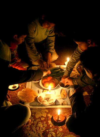 Una familia palestina come bajo la luz de velas y linternas de gas tras el bloqueo de Israel.