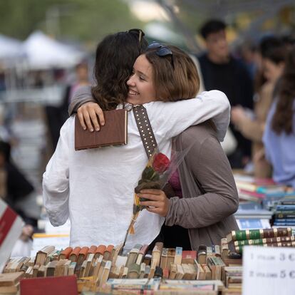 Dos amigas se abrazan tras regalarse libros y rosas en la plaza Catalunya.