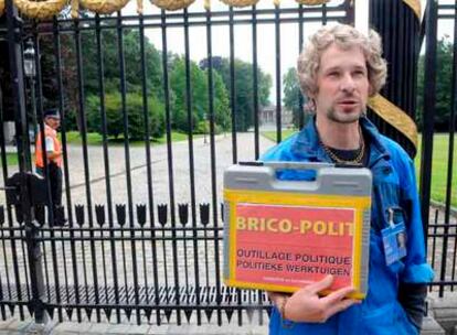 El cómico belga Nabsurde posa ante el Palacio Real disfrazado de carpintero y sosteniendo una caja en la que puede leerse "Kit de brico-política, herramientas políticas", esta tarde en Laeken durante la reunión entre el Rey y Leterme