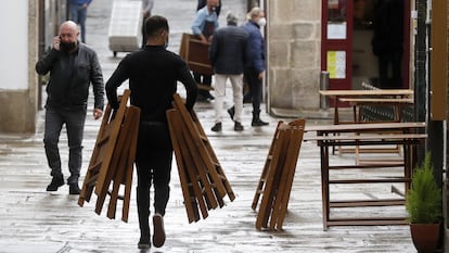 Un camarero monta una terraza en una calle de Santiago de Compostela.