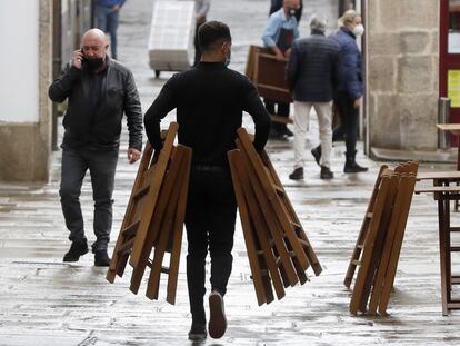 Un camarero monta una terraza en una calle de Santiago de Compostela.