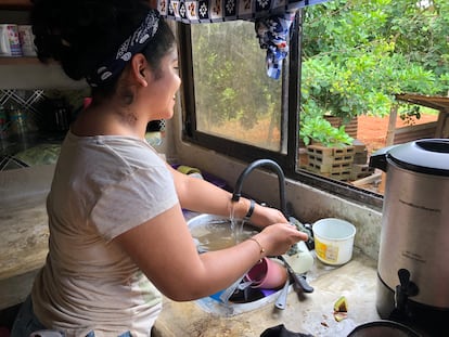 Una mujer lava trastes con el agua del grifo que sale contaminada.