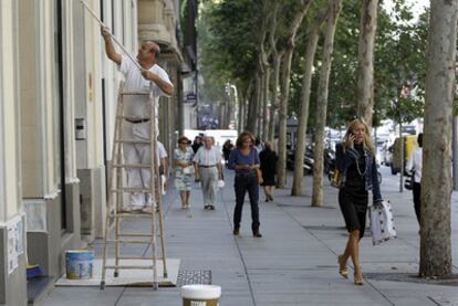 Un operario da los últimos toques de pintura a una fachada, en la acera de los números pares.