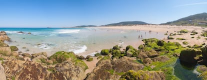 Doniños, Ferrol (A Coruña). La base naval de Ferrol siempre fue muy deseada por su estratégica ubicación. Doniños era el playazo más cercano a la localidad coruñesa y, por sus casi dos kilómetros, idóneo para el desembarco inglés del 25 de agosto de 1800, origen de la batalla de Brión (que cumple este año su 222º aniversario), que se recrea aquí a finales de agosto. Hoy es el arenal ferrolano que concita mayor ambiente, con bandadas de jinetes sobre tablas dispuestos a sacar partido de los trenes de olas que rebotan en este bravío playón muy arriesgado para el baño. Los ‘green jackets’ fueron repelidos en el castillo de San Felipe y en La Graña, de donde retrocedieron hasta embarcar en su escuadra. Napoleón, al enterarse, dijo: “Brindad por los valientes ferrolanos”. 