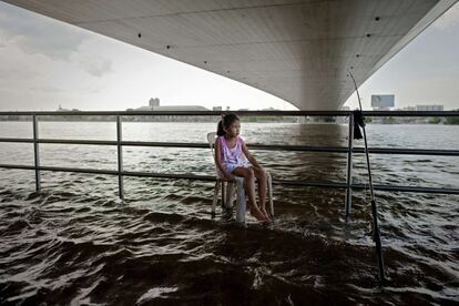 Un niña sentada a orillas de río Chao Praya en Bangkok