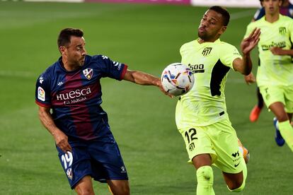 El defensa brasileño del Atlético de Madrid Renan Lodi pelea por el control del balón con el jugador de la SD Huesca, Pedro López, durante el partido de la cuarta jornada de Liga en Primera División que disputan este miércoles en el estadio El Alcoraz.