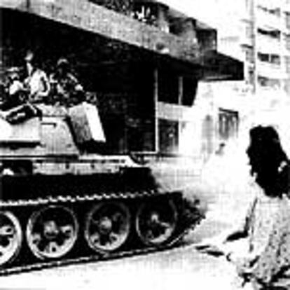 Una beirutí lanza arroz al paso de un carro de combate del Ejército regular tras la caída de Aún