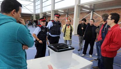 Una pareja de los  Mossos d’Esquadra, ante una urna durante la jornada del 1-O. 