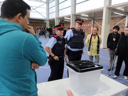 Una pareja de los  Mossos d’Esquadra, ante una urna durante la jornada del 1-O. 