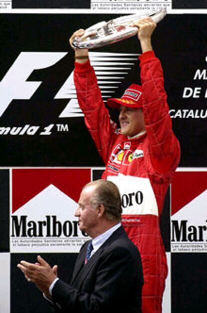 Schumacher levanta el trofeo mientras el Rey aplaude.