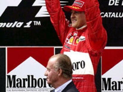 Schumacher levanta el trofeo mientras el Rey aplaude.