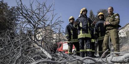 Bombeiros palestinos ao lado de um militar israelense.