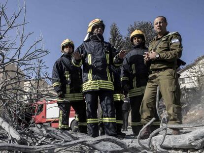 Bombeiros palestinos ao lado de um militar israelense.