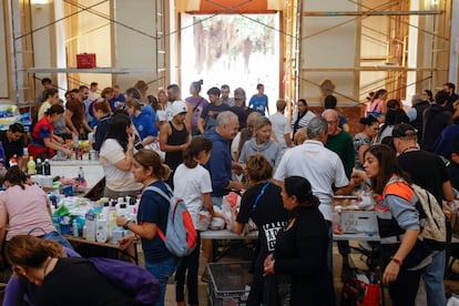 Vecinos de La Torre, Valencia, asisten a la parroquia de Nuestra Señora de Gracia donde se ha instalado un punto de recogida de alimentos y productos de primera necesidad, este viernes. 