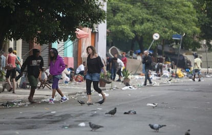 Pessoas caminham em rua suja na cracolândia, região central de São Paulo.