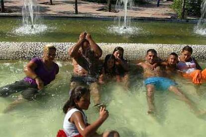 Un grupo de personas se refresca en una fuente de lo que fue el recinto de la Expo de Sevilla.