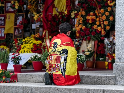 Un hombre envuelto en un bandera preconstitucional se arrodilla frente al panteón de la familia Franco, en el cementerio de Mingorrubio, en El Pardo, Madrid.