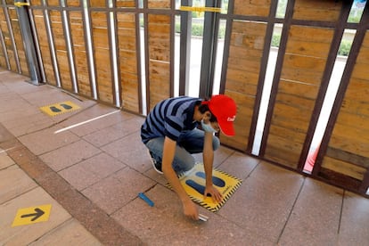 Un trabajador coloca pegatinas en el suelo para mantener la distancia social en un centro comercial antes de su reapertura en Nueva Delhi (India).