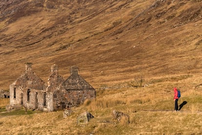Un excursionista junto a una granja abandonada en las Highlands.