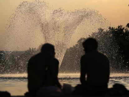 Dos personas conversan con la fuente del Templo de Debod de fondo.