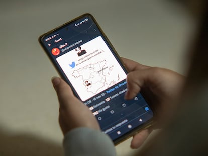 A woman looks at a Twitter meme on a cellphone.