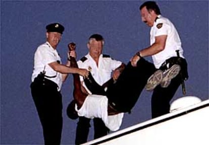 Tres policías bajan del techo del autobús a uno de los amotinados el pasado día 6.