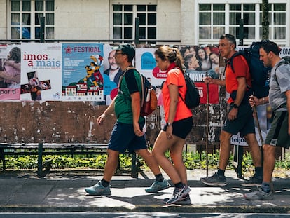 Un grupo de peregrinos pasa delante de carteles electorales, este sábado en Santiago de Compostela (A Coruña).