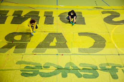 Unos vecinos de Manzanares el Real, confeccionan batas con una pancarta donada por Greenpeace.