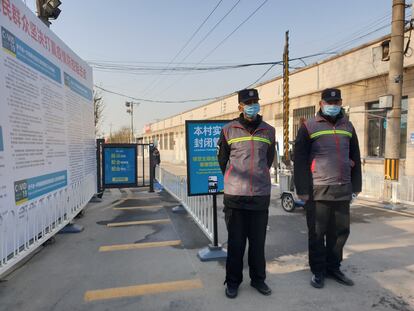 Dos trabajadores comunitarios vigilan un puesto de control en Heizhuanghu, Pekín