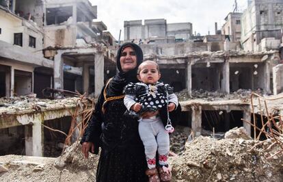 Una mujer posa con su nieta entre los escombros de un barrio de Raqa.