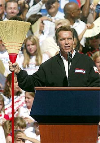 Arnold Schwarzenegger muestra una escoba, el domingo, durante su mitin fin de campaña en Sacramento.