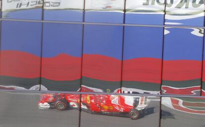 Un monoplaza de Ferrari se refleja en una cristalera durante la carrera.