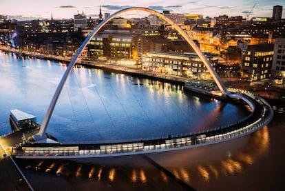 Más que un puente, es una manifestación arquitectónica: este enorme arco de acero que une las dos orillas del Tyne es el primer puente basculante del mundo. Su recorrido rotativo —pero fijo en sus dos extremos— proporciona a peatones y ciclistas una divertida conexión entre Gateshead y Newcastle, a través de la rehabilitada zona portuaria. Además, como todo el conjunto —el camino peatonal y el arco de contrapeso, de 50 metros de altura— oscila sobre los puntales, permite el paso de barcos grandes con una maniobra de bajo consumo. Muchos lo llaman el ‘Winking Eye Bridge’ (puente del ojo guiñado), por su forma y por cómo se eleva. <a href="https://www.gateshead.gov.uk/article/4594/The-Gateshead-Millennium-Bridge" target="_blank"> El puente</a> enlaza el artístico barrio de Quays, que acoge, en la orilla sur, el recinto musical The Sage y el BALTIC Centre for Contemporary Art, con el de Quayside de Newcastle, en la orilla norte.