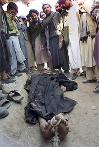 Un grupo de habitantes de Kunduz rodea el cadáver de un talibán.