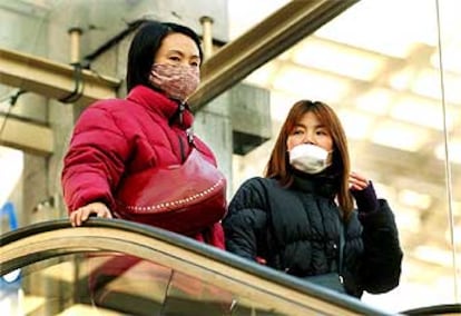 Dos mujeres, con mascarilla para protegerse de la epidemia, en la estación de trenes de Shanghai.