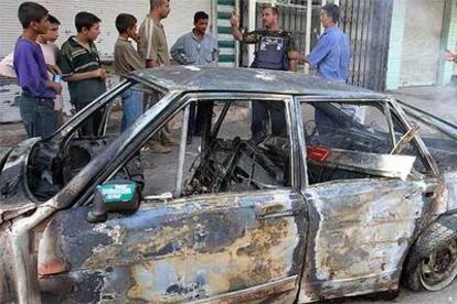 Un grupo de iraquíes observa en la ciudad norteña de Mosul un coche destrozado por el ataque terrorista.