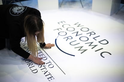 A woman cleans the logo of the WEF, on the first day of the 54th annual meeting of the World Economic Forum (WEF), in Davos.