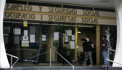 Dos personas esperan en las puertas de la oficina de Empleo y Seguridad Social de Barcelona.
