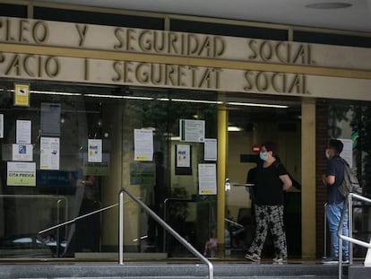 Dos personas esperan en las puertas de la oficina de Empleo y Seguridad Social de Barcelona.